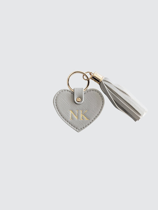 Heart-shaped keychain with 'NK' initials on a light gray background